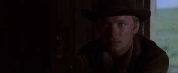 Movie still from “Unforgiven” (1992), directed by Clint Eastwood – A man wearing a cowboy hat in a dark room; Close Up shot, Low angle