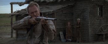 Movie still from “Unforgiven” (1992), directed by Clint Eastwood – A man holding a gun while standing next to a woman; Close Up shot, Low angle