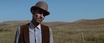 Movie still from “Unforgiven” (1992), directed by Clint Eastwood – A man wearing a hat standing in the middle of a field; Close Up shot, Low angle