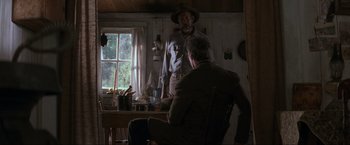 Movie still from “Unforgiven” (1992), directed by Clint Eastwood – A man in a cowboy hat is standing in front of another man in a cowboy hat; Wide shot, Low angle