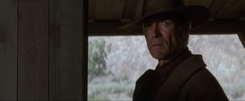 Movie still from “Unforgiven” (1992), directed by Clint Eastwood – A person wearing a hat near a window; Close Up shot, Low angle