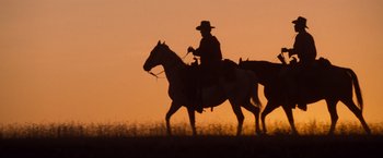 Movie still from “Unforgiven” (1992), directed by Clint Eastwood – A man is riding a horse in the sunset; Wide shot, Low angle