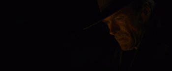 Movie still from “Unforgiven” (1992), directed by Clint Eastwood – A man in a hat is looking into the dark; Close Up shot, Low angle