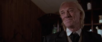 Movie still from “Unforgiven” (1992), directed by Clint Eastwood – An older man wearing a suit and tie in a room; Close Up shot, Low angle