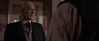 Movie still from “Unforgiven” (1992), directed by Clint Eastwood – An older man wearing a suit and tie talking to another man; Close Up shot, Over the shoulder angle