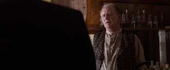 Movie still from “Unforgiven” (1992), directed by Clint Eastwood – An older man wearing a suit looking at himself in the mirror; Close Up shot, Over the shoulder angle