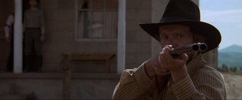 Movie still from “Unforgiven” (1992), directed by Clint Eastwood – A man holding a gun in his right hand while wearing a cowboy hat; Close Up shot, Low angle