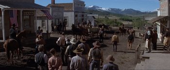 Movie still from “Unforgiven” (1992), directed by Clint Eastwood – A group of men standing in front of a horse drawn carriage; Extreme Wide shot, Low angle