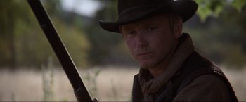 Movie still from “Unforgiven” (1992), directed by Clint Eastwood – A man with a hat holding a gun in his hand; Close Up shot, Low angle
