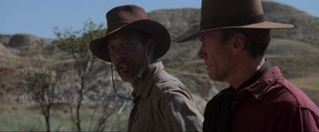 Movie still from “Unforgiven” (1992), directed by Clint Eastwood – Two men wearing hats and standing next to each other on a hill; Close Up shot, Over the shoulder angle