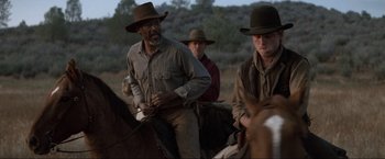 Movie still from “Unforgiven” (1992), directed by Clint Eastwood – A group of men riding on the backs of horses; Medium shot, Over the shoulder angle