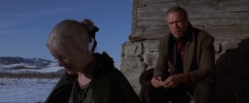 Movie still from “Unforgiven” (1992), directed by Clint Eastwood – A man and a woman sitting next to each other on the ground; Medium shot, Low angle
