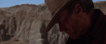Movie still from “Unforgiven” (1992), directed by Clint Eastwood – A person wearing a cowboy hat; Close Up shot, Over the shoulder angle