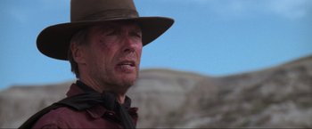 Movie still from “Unforgiven” (1992), directed by Clint Eastwood – A man wearing a hat and a red shirt; Close Up shot, Low angle