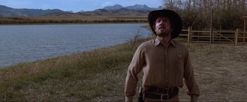 Movie still from “Unforgiven” (1992), directed by Clint Eastwood – A man standing in front of a body of water; Medium shot, Low angle