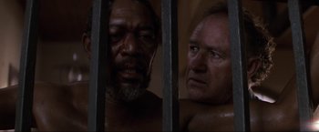 Movie still from “Unforgiven” (1992), directed by Clint Eastwood – Two men are standing next to each other in a jail cell; Close Up shot, High angle