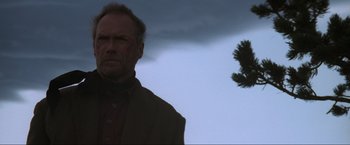 Movie still from “Unforgiven” (1992), directed by Clint Eastwood – An older man standing in front of a tree; Medium shot, Low angle