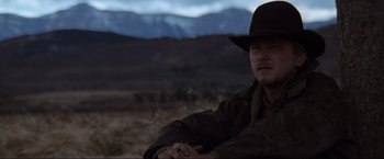 Movie still from “Unforgiven” (1992), directed by Clint Eastwood – A man wearing a hat sitting in a field; Close Up shot, Low angle