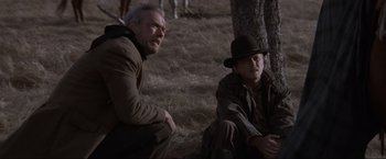 Movie still from “Unforgiven” (1992), directed by Clint Eastwood – Two men sitting next to each other on the ground; Medium shot, Low angle