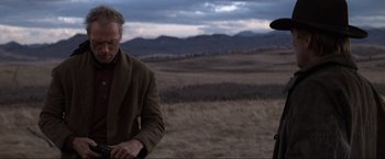 Movie still from “Unforgiven” (1992), directed by Clint Eastwood – A man standing in the middle of an open field; Medium shot, Over the shoulder angle