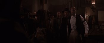 Movie still from “Unforgiven” (1992), directed by Clint Eastwood – A group of men standing next to each other in the dark; Medium shot, Low angle