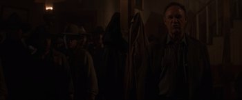 Movie still from “Unforgiven” (1992), directed by Clint Eastwood – A group of people standing in a dark room; Medium shot, Low angle