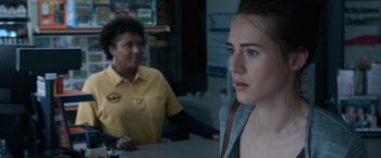 A woman standing next to a woman sitting at a counter
