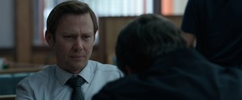 A man wearing a suit and tie talking to another man wearing a suit and tie