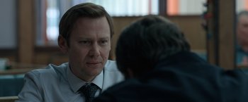 A man wearing a suit and tie talking to another man wearing a suit and tie