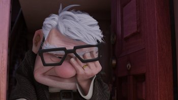 Movie still from “Up” (2009), directed by Bob Peterson – An old man wearing glasses and holding his hand to his face; Close Up shot, Over the shoulder angle
