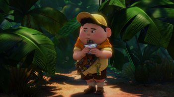 Movie still from “Up” (2009), directed by Bob Peterson – A boy in a yellow shirt and brown hat is standing in the jungle; Wide shot, High angle