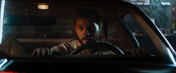 Movie still from “Upgrade” (2018), directed by Leigh Whannell – A man sitting in the drivers seat of a car; Close Up shot, Over the shoulder angle