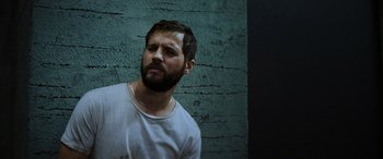 Movie still from “Upgrade” (2018), directed by Leigh Whannell – A man with a goatee is looking down; Close Up shot, Low angle