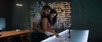 Movie still from “Upgrade” (2018), directed by Leigh Whannell – A man and a woman standing next to a glass table; Medium shot, Overhead angle