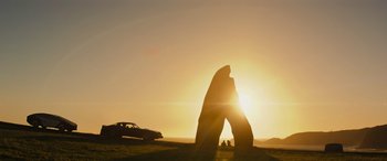 Movie still from “Upgrade” (2018), directed by Leigh Whannell – A car parked in front of a large rock formation; Extreme Wide shot, Low angle