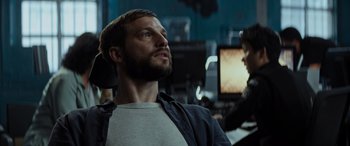 Movie still from “Upgrade” (2018), directed by Leigh Whannell – A man with a beard is sitting in front of a computer; Close Up shot, Low angle
