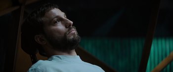 Movie still from “Upgrade” (2018), directed by Leigh Whannell – A man with a goatee looking up at the sky; Close Up shot, Low angle