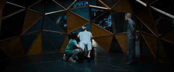 Movie still from “Upgrade” (2018), directed by Leigh Whannell – A man sitting on a chair next to a woman; Wide shot, High angle