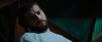 Movie still from “Upgrade” (2018), directed by Leigh Whannell – A man with his eyes closed sitting in a chair; Close Up shot, Low angle