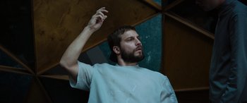 Movie still from “Upgrade” (2018), directed by Leigh Whannell – A man with a beard is holding something in his hand; Medium shot, Low angle