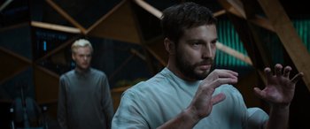 Movie still from “Upgrade” (2018), directed by Leigh Whannell – A man standing in front of another man in a room; Medium shot, Low angle