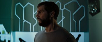 Movie still from “Upgrade” (2018), directed by Leigh Whannell – A man with a beard is standing in front of a wall; Close Up shot, Low angle