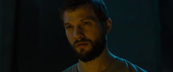 Movie still from “Upgrade” (2018), directed by Leigh Whannell – A man with a goatee and a beard stares at the camera; Close Up shot, Low angle