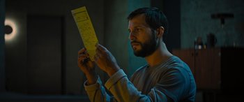 Movie still from “Upgrade” (2018), directed by Leigh Whannell – A man looking at a piece of paper in his hands; Close Up shot, Low angle