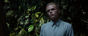 Movie still from “Upgrade” (2018), directed by Leigh Whannell – A man in a shirt and tie standing in front of trees; Close Up shot, Low angle