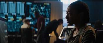 Movie still from “Upgrade” (2018), directed by Leigh Whannell – A group of people standing in front of a computer screen; Medium shot, Over the shoulder angle