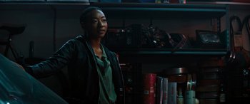 Movie still from “Upgrade” (2018), directed by Leigh Whannell – A woman standing in front of a bookshelf; Medium shot, Over the shoulder angle