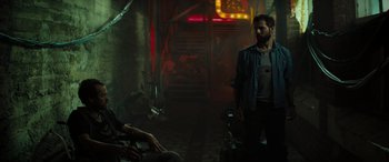 Movie still from “Upgrade” (2018), directed by Leigh Whannell – A man standing next to another man in a dark room; Wide shot, Over the shoulder angle