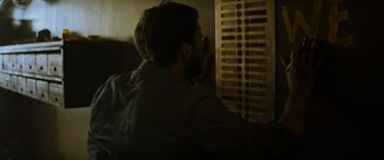 Movie still from “Upgrade” (2018), directed by Leigh Whannell – A bearded man leaning against a wall with his hand to his face; Extreme Close Up shot, Low angle