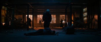 Movie still from “Upgrade” (2018), directed by Leigh Whannell – A person is lying on the ground in a dark room; Wide shot, Low angle
